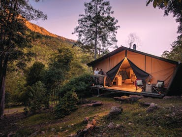 Romantic couple enjoy the change in light from the safari tent deck as night falls.
