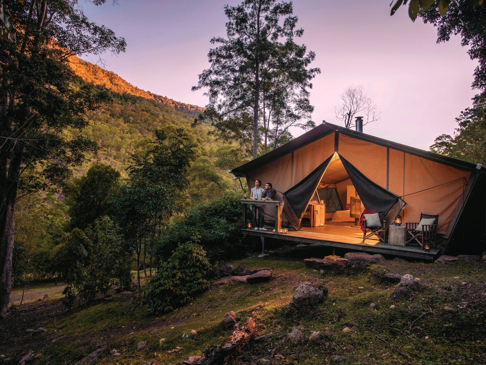 Romantic couple enjoy the change in light from the safari tent deck as night falls. Romantic couple enjoy the change in light from the safari tent deck as night falls.