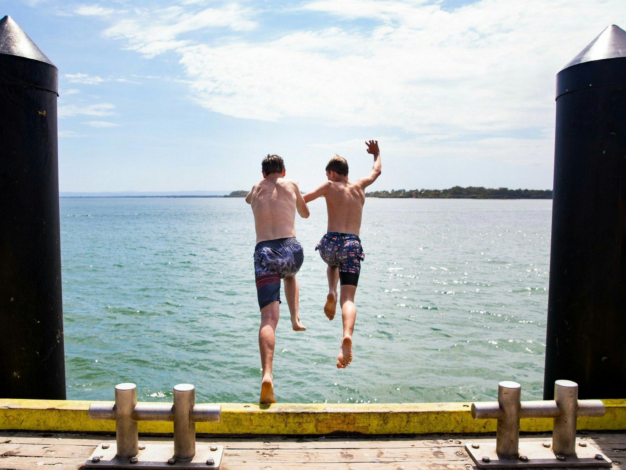 Boys jumping into the water at Bribie Island