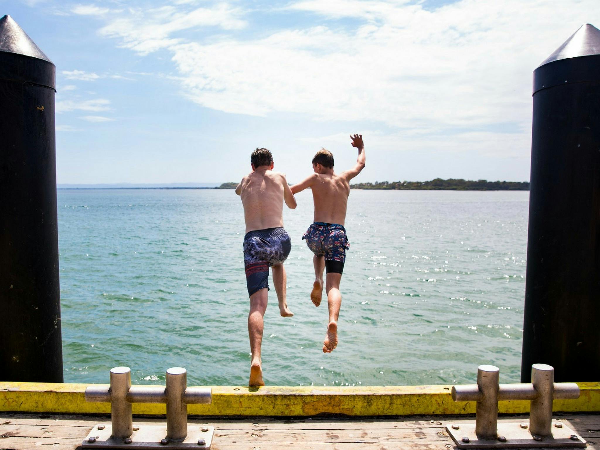 Boys jumping into the water at Bribie Island