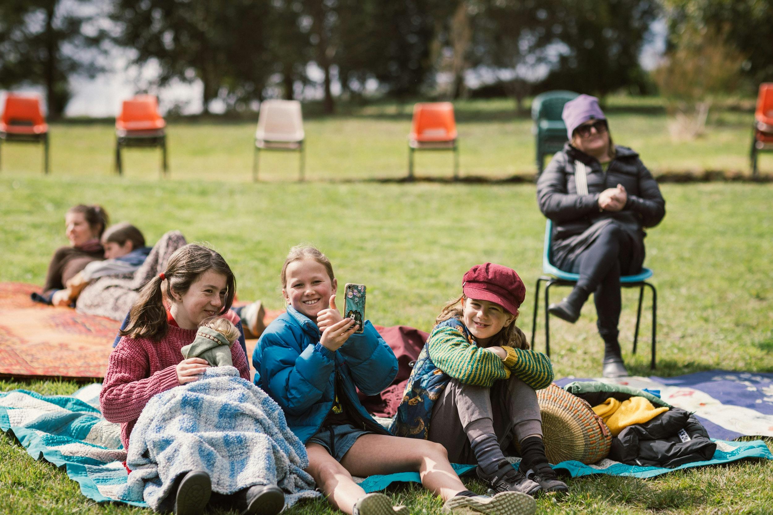Three children are sitting on a blanket at Premaydena Garden.
