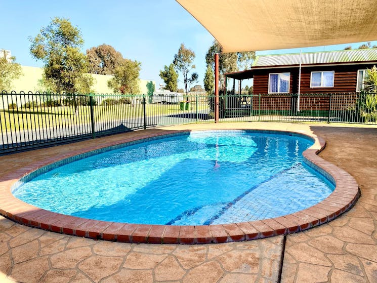 Round shaped pool with bricks around it and a shade cover