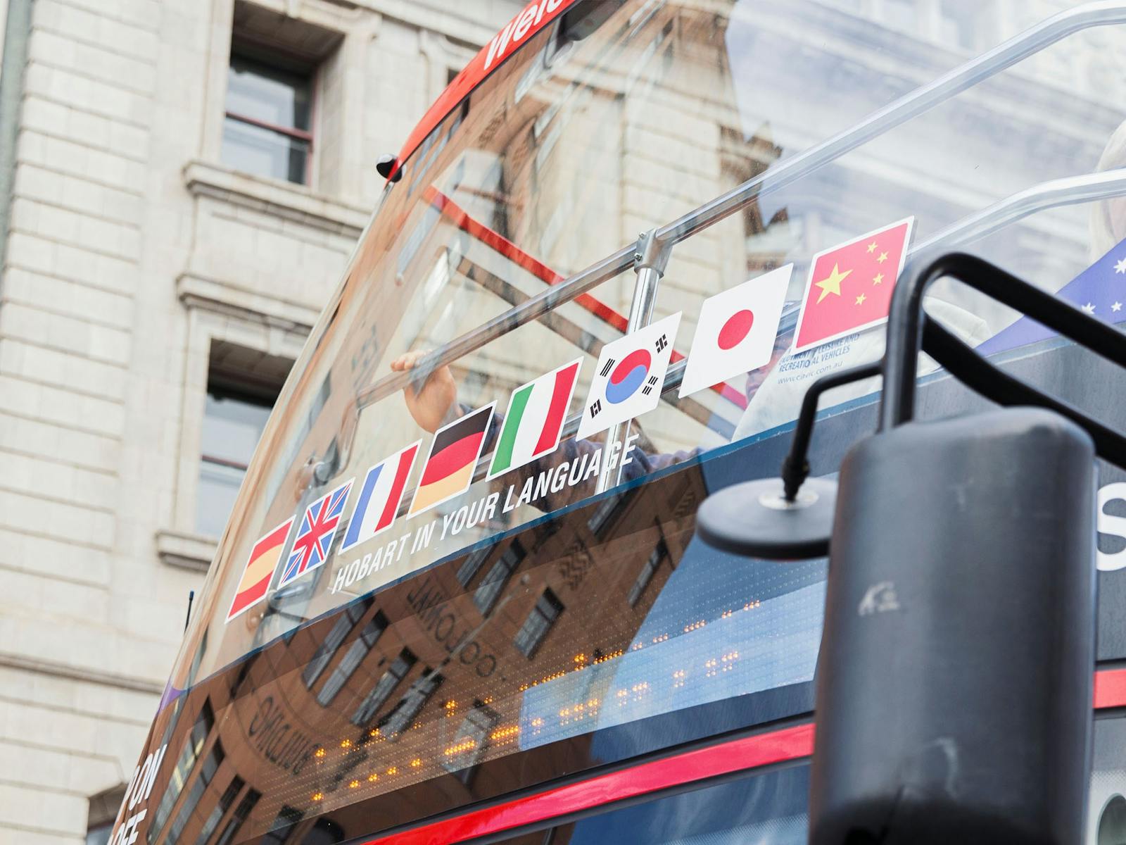 Bus displaying Chinese, English, French, German, Italian,  Japanese, Korean and Spanish flags.