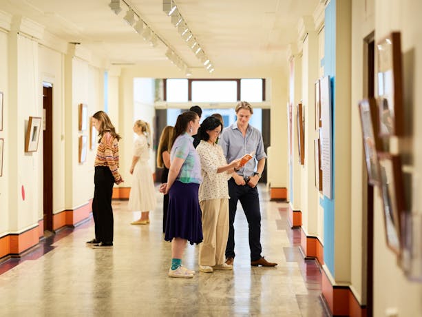 A group of people standing in a gallery looking at pictures on the walls