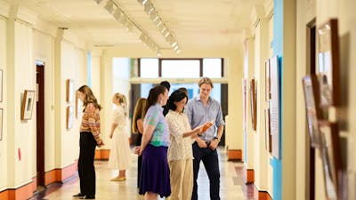 A group of people standing in a gallery looking at pictures on the walls