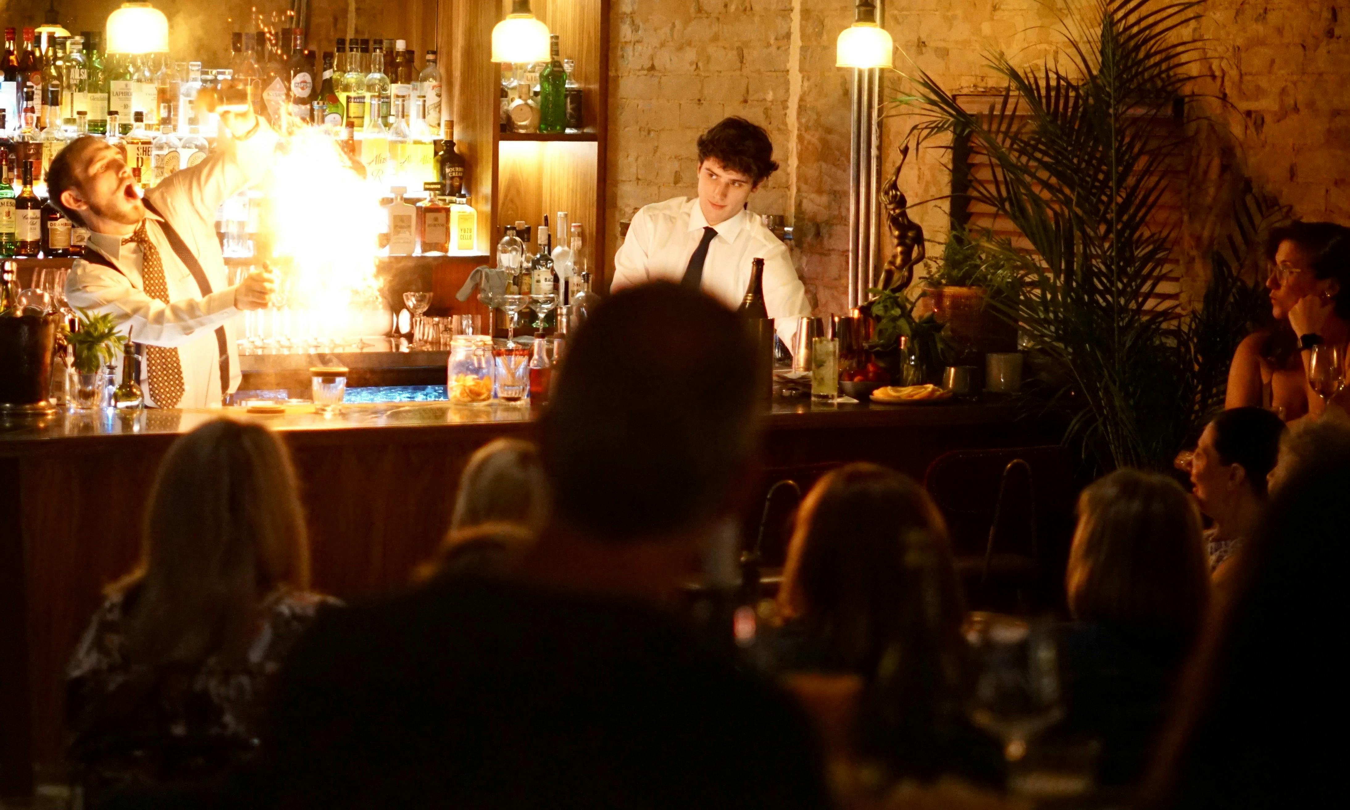 performing bartender flames cinnamon at the bar in a flash of light before an audience