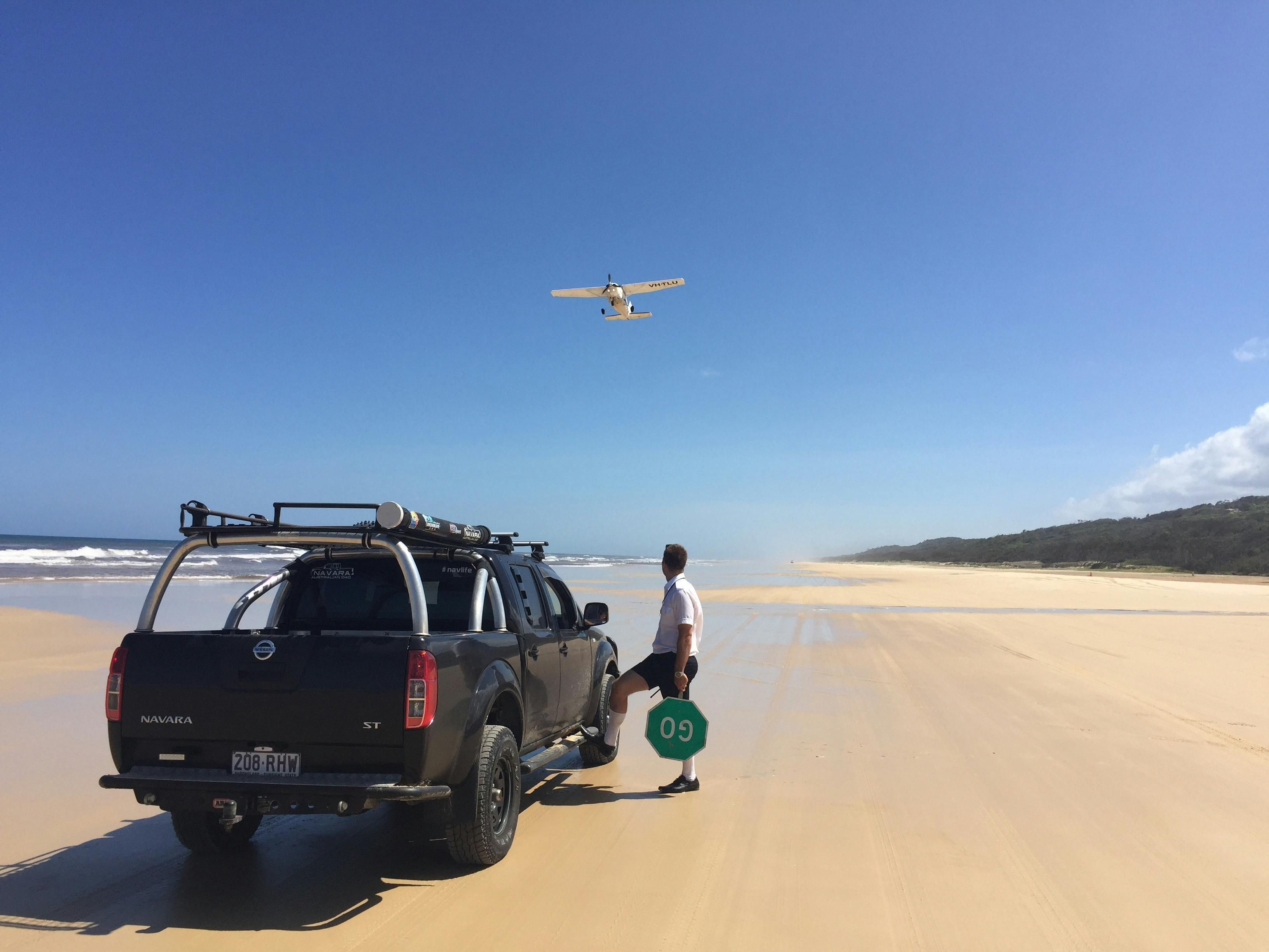 photo of 4wd vehicle stopped on Fraser island eastern beach while small plane takes off from beach
