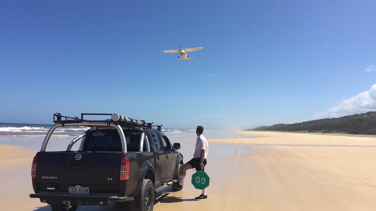 photo of 4wd vehicle stopped on Fraser island eastern beach while small plane takes off from beach