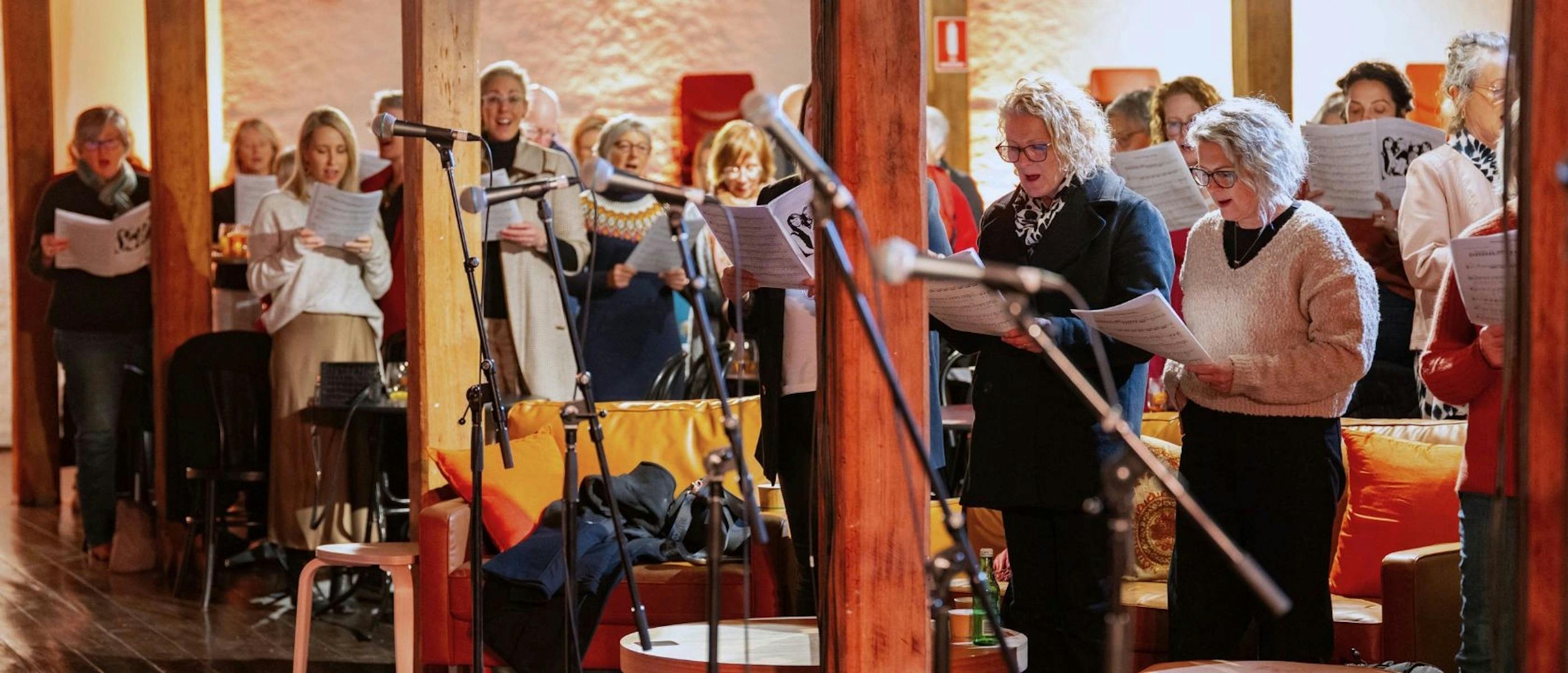 A group of people holding song books singing together.
