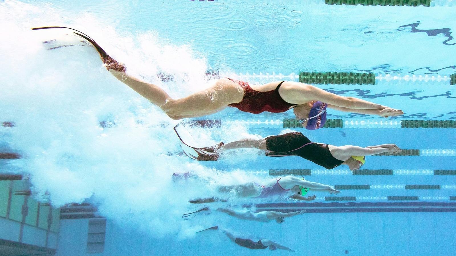 Pool rescue competitors race with fins for maximum speed in a rescue situation