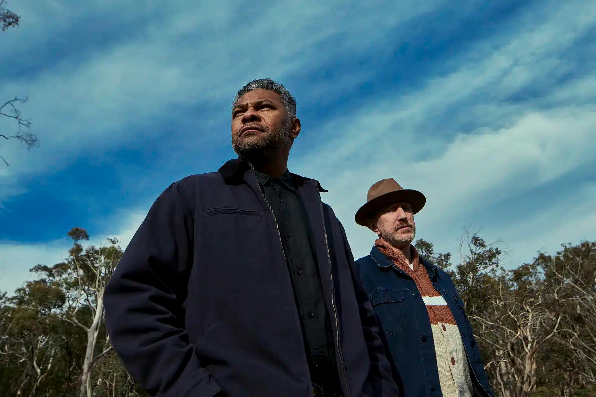 Artists standing together under trees and open blue sky
