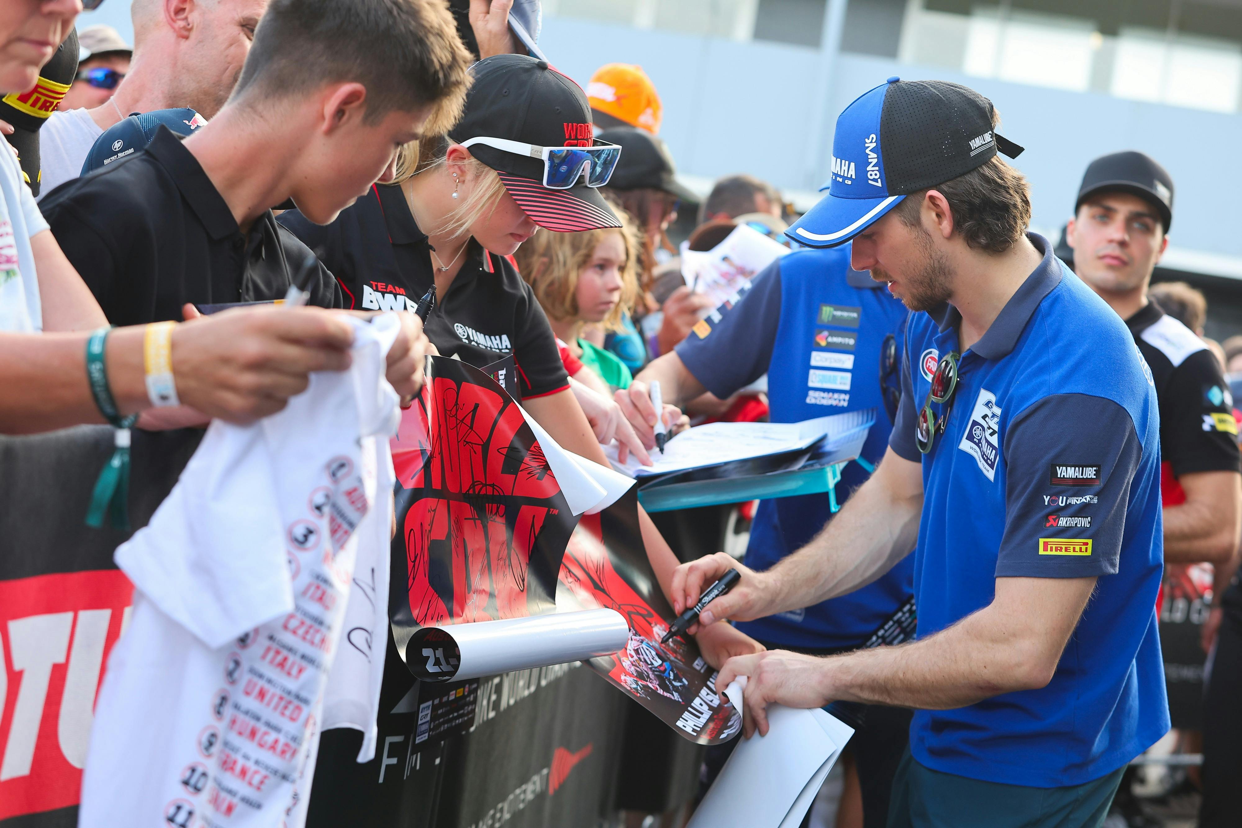 WorldSBK rider signing autographs for fans.