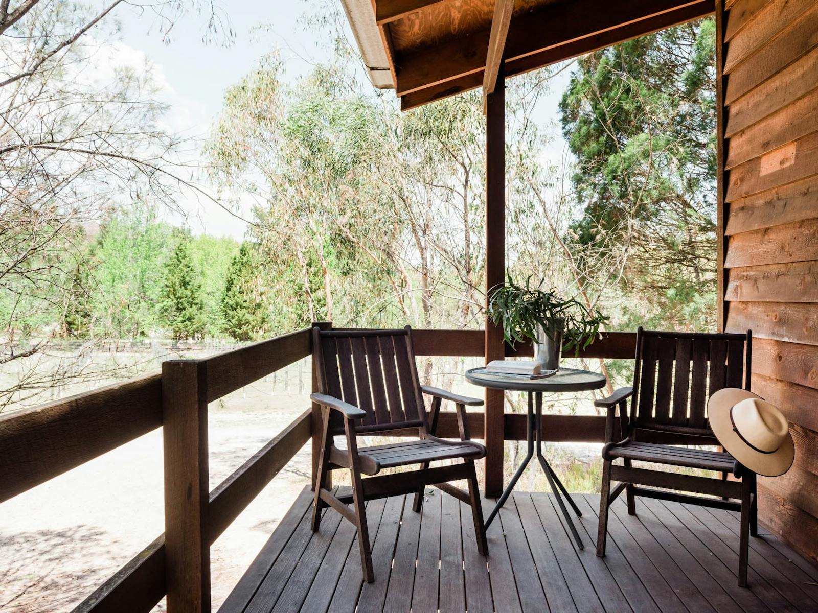 Outdoor chairs on timber cabin verandah with view of bushland behind Outdoor chairs on timber cabin verandah with view of bushland behind