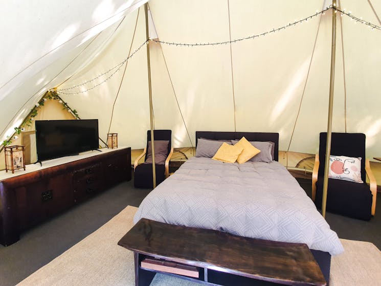 Tv and queen bed in a glamping tent