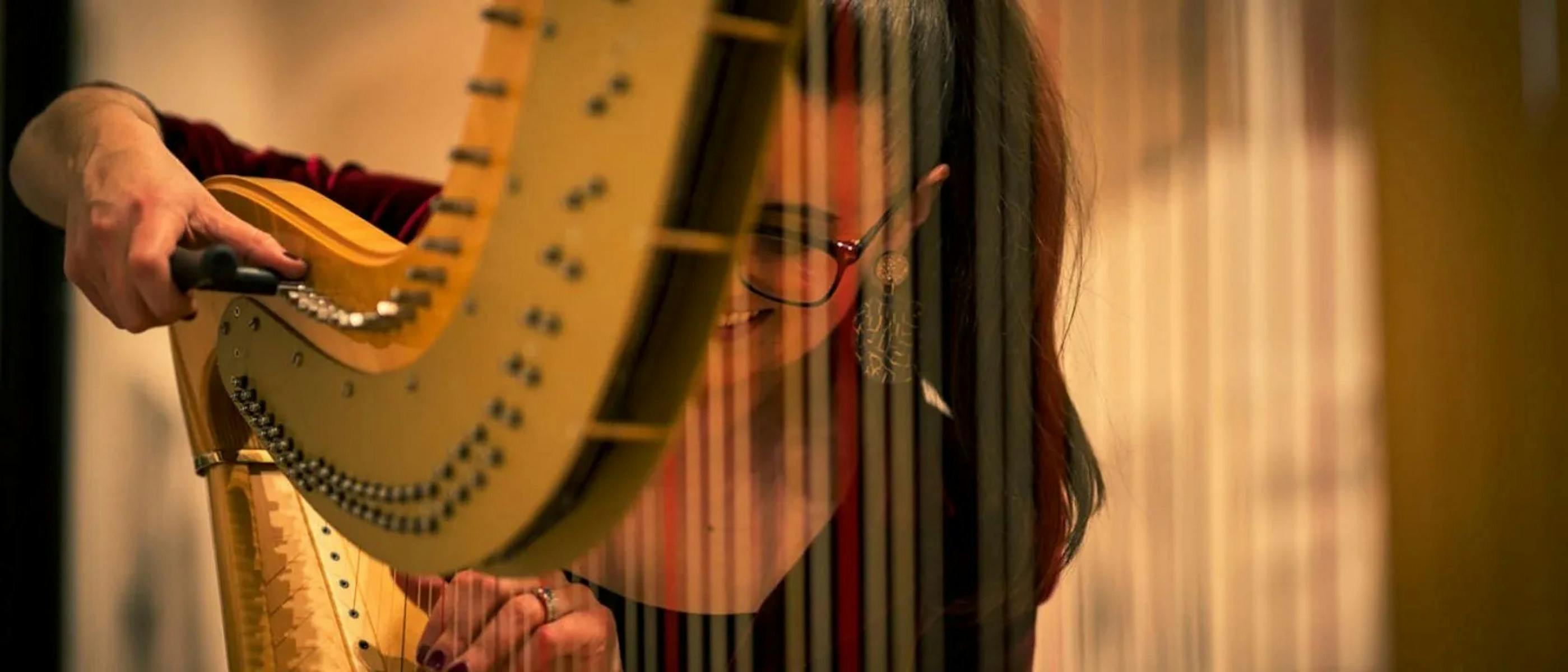 A woman smiling and holding a harp