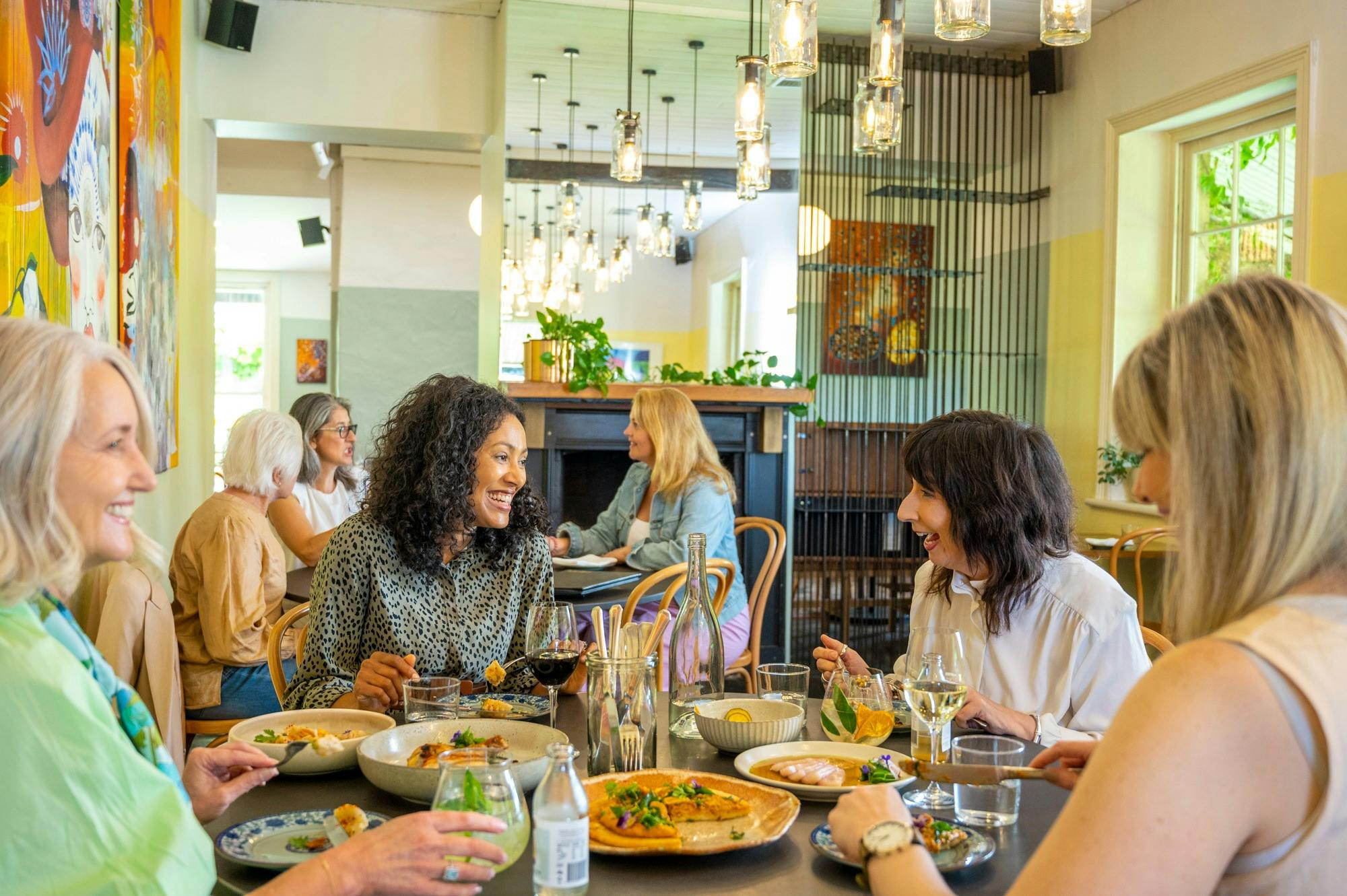 Groups of women having lunch and chatting and laughing
