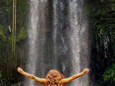 Woman standing in the water in front of Millaa Millaa Falls on the Atherton Tablelands