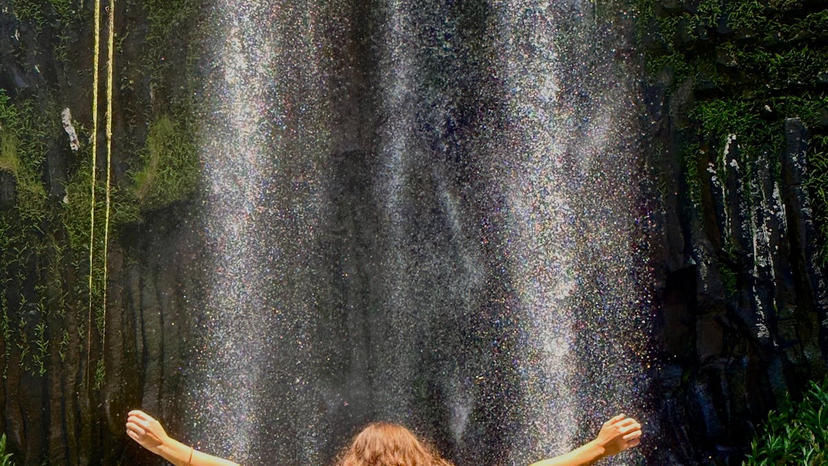 Woman standing in the water in front of Millaa Millaa Falls on the Atherton Tablelands