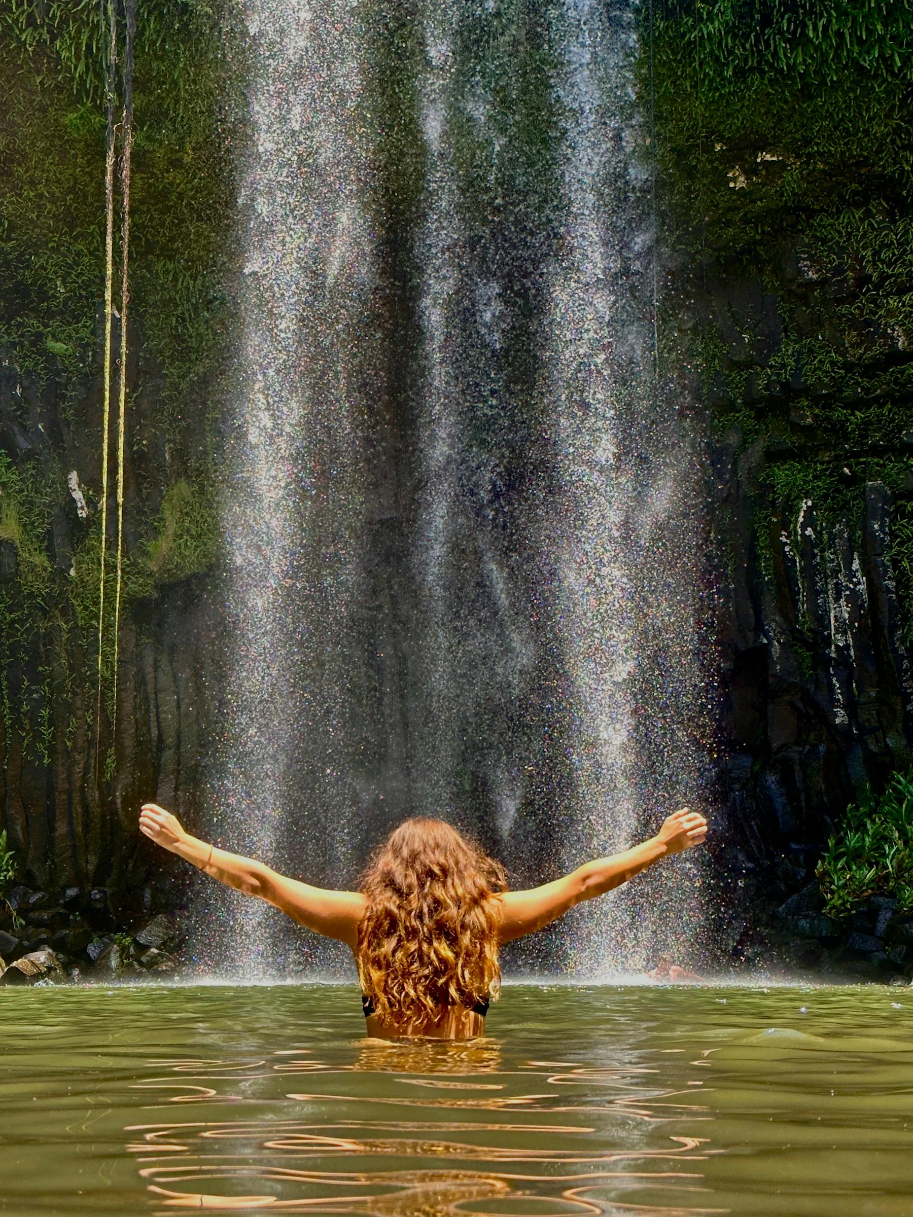 Woman standing in the water in front of Millaa Millaa Falls on the Atherton Tablelands