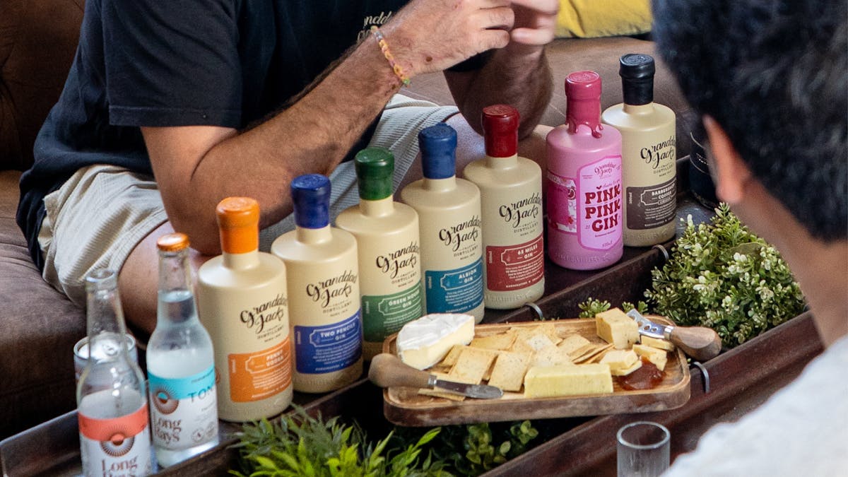 Gin tasting experience with Granddad Jack’s bottled spirits and cheese board on a shared table.