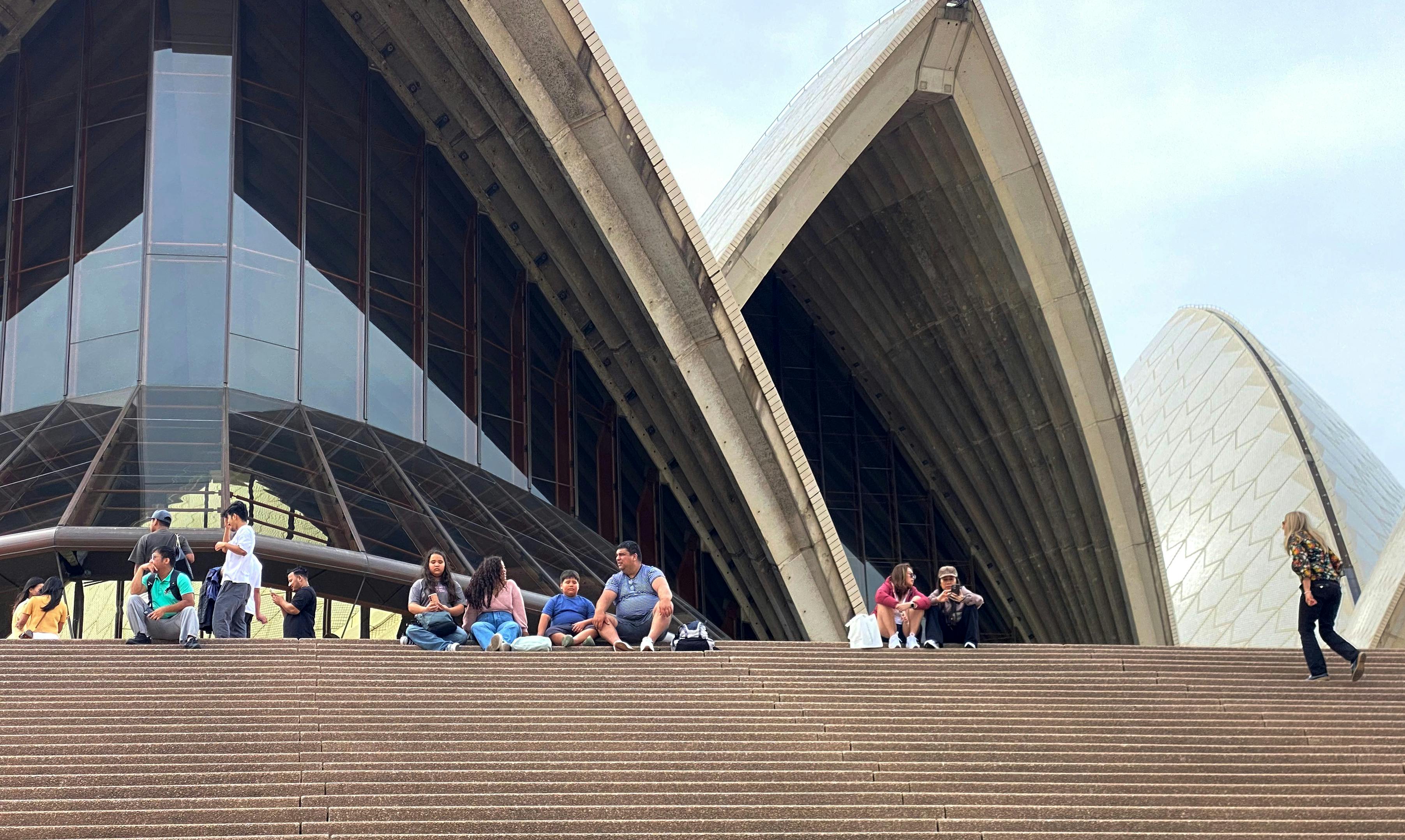 Besucher entspannen sich auf den Stufen des Opernhauses bei einer privaten Tour durch das Innere des Opernhauses.