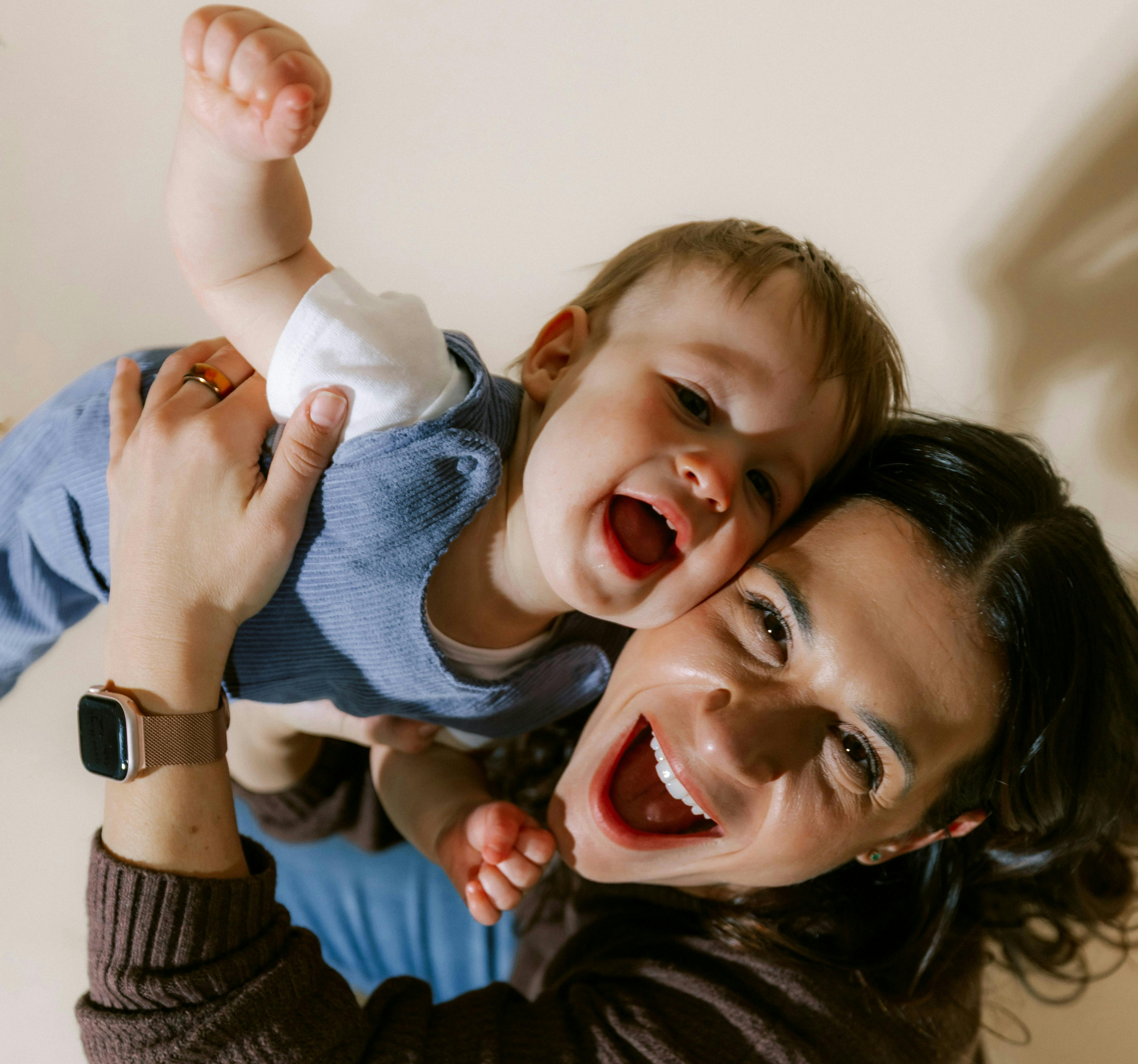 Laughing mother holding laughing baby