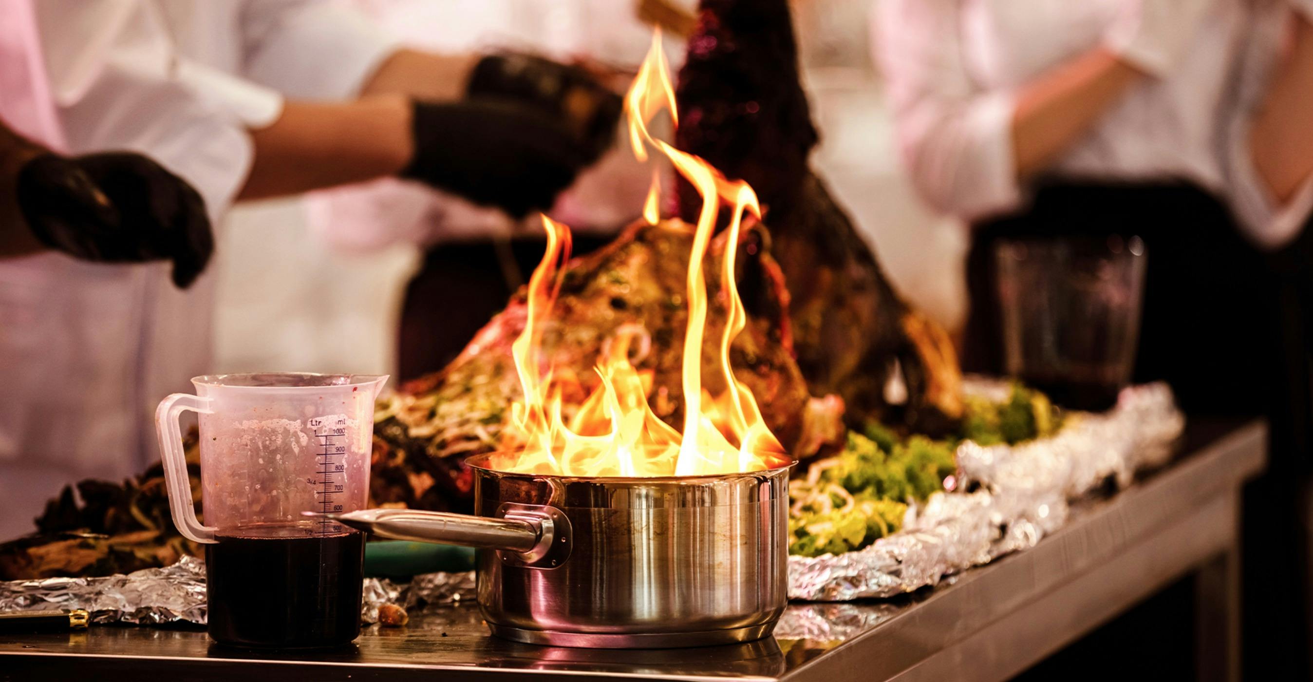A flaming saucepan on a bench in a kitchen