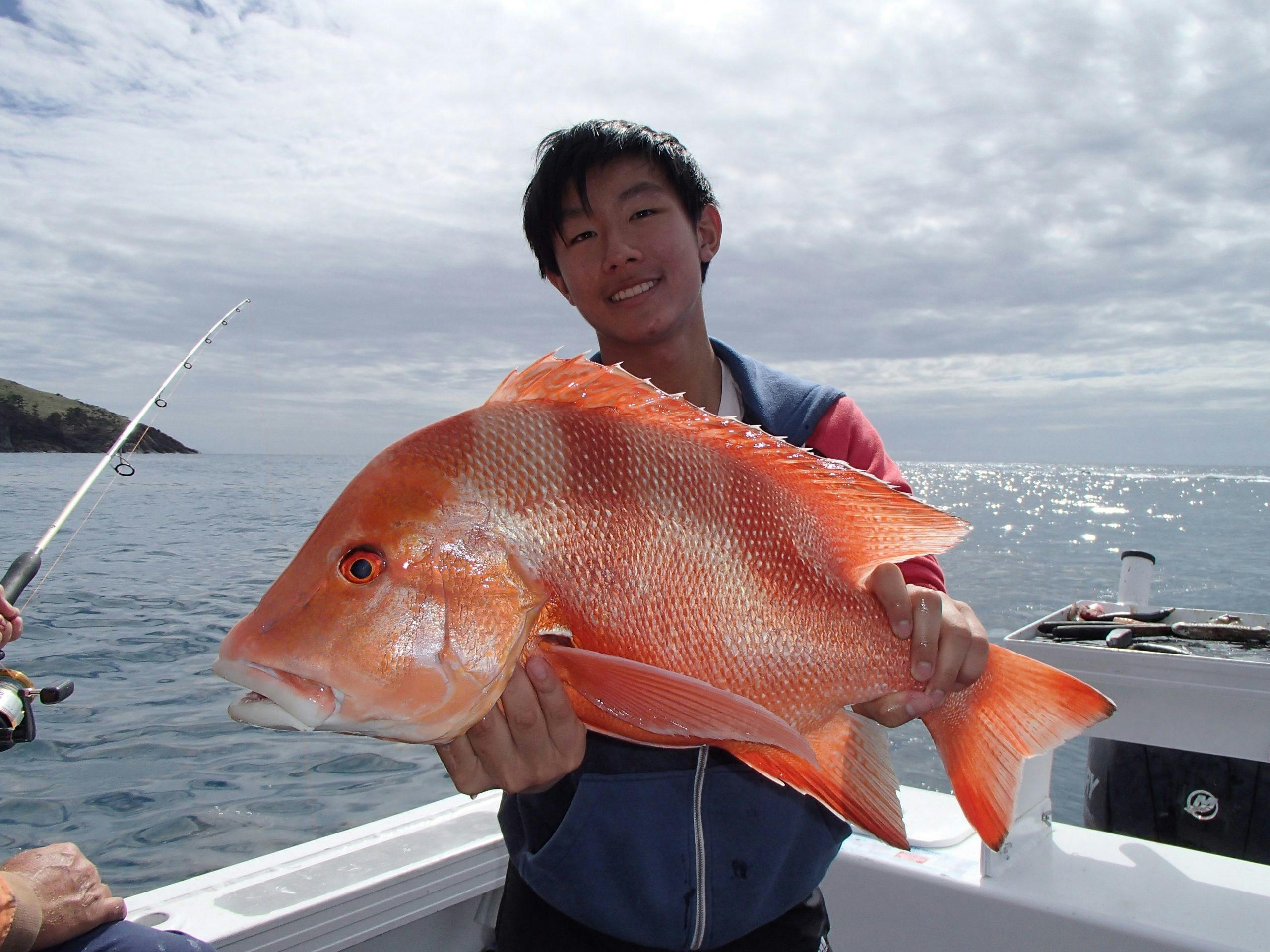 Picture has a angler holding a large red throat emperor that he has caught, he is on the boat.