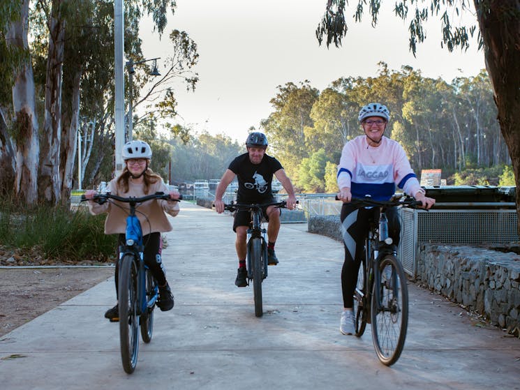 Girl, Man and Lady riding bikes at the Riverboat Dock Echuca