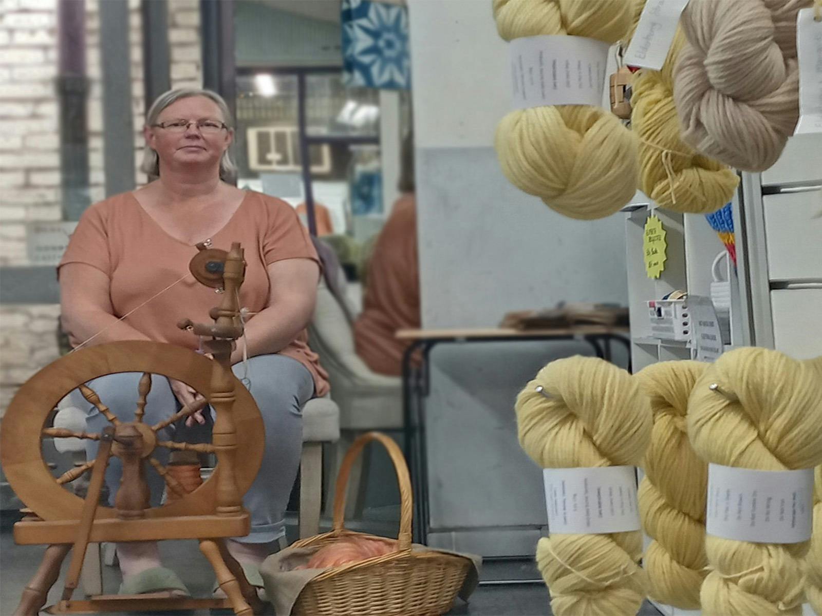 A woman sitting next to her spinning wheel