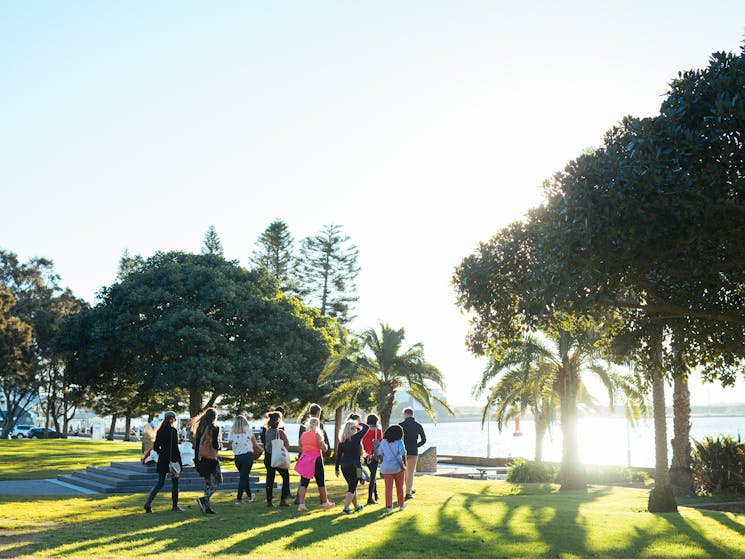 A small group walks on Newcastle foreshore on a guided Newcastle Afoot walking tour