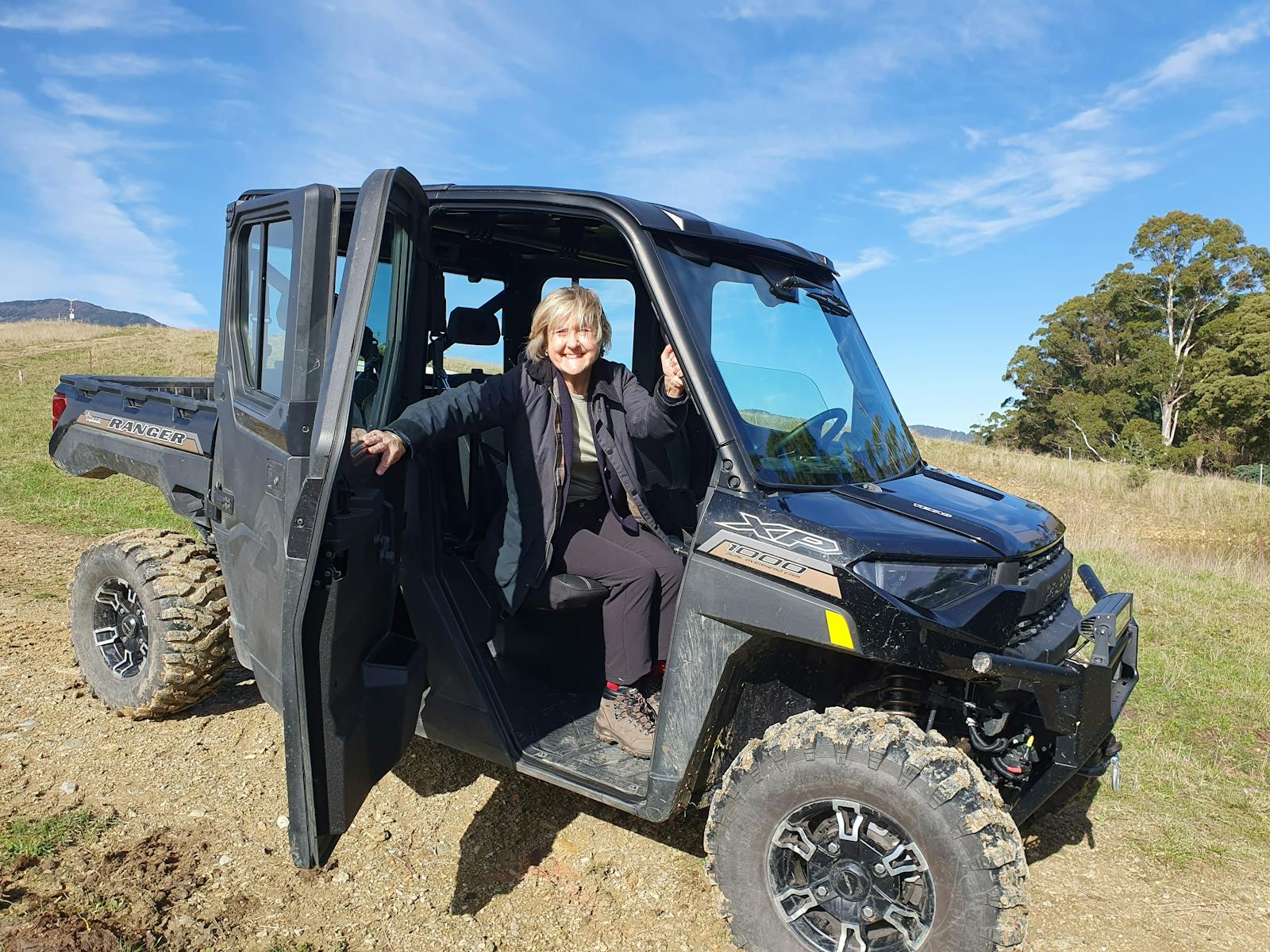 Woman sitting in front seat of ATV with door open and smiling