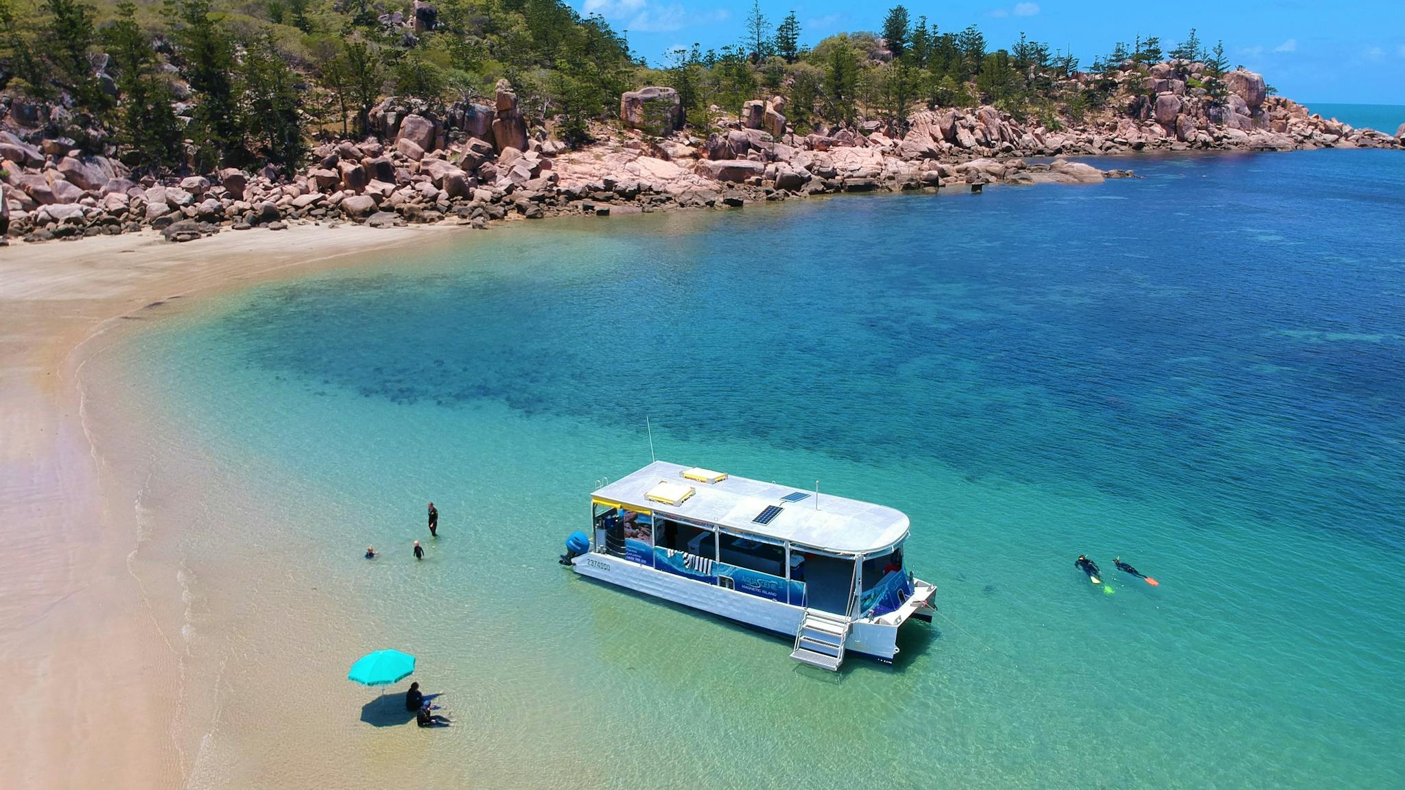 Aquascene boat in clear blue shallow water near beach edge with people swimming and sitting on beach Aquascene boat in clear blue shallow water near beach edge with people swimming and sitting on beach