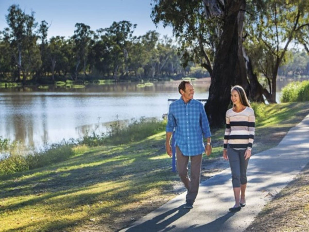 Man and Woman walking on a path next to a river