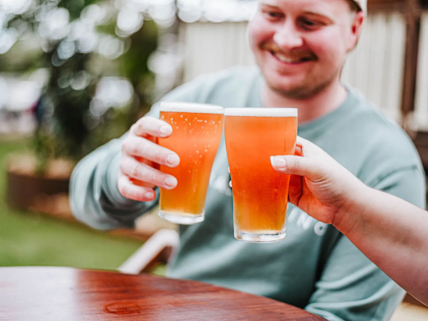 Man doing a cheers with a person holding a beer