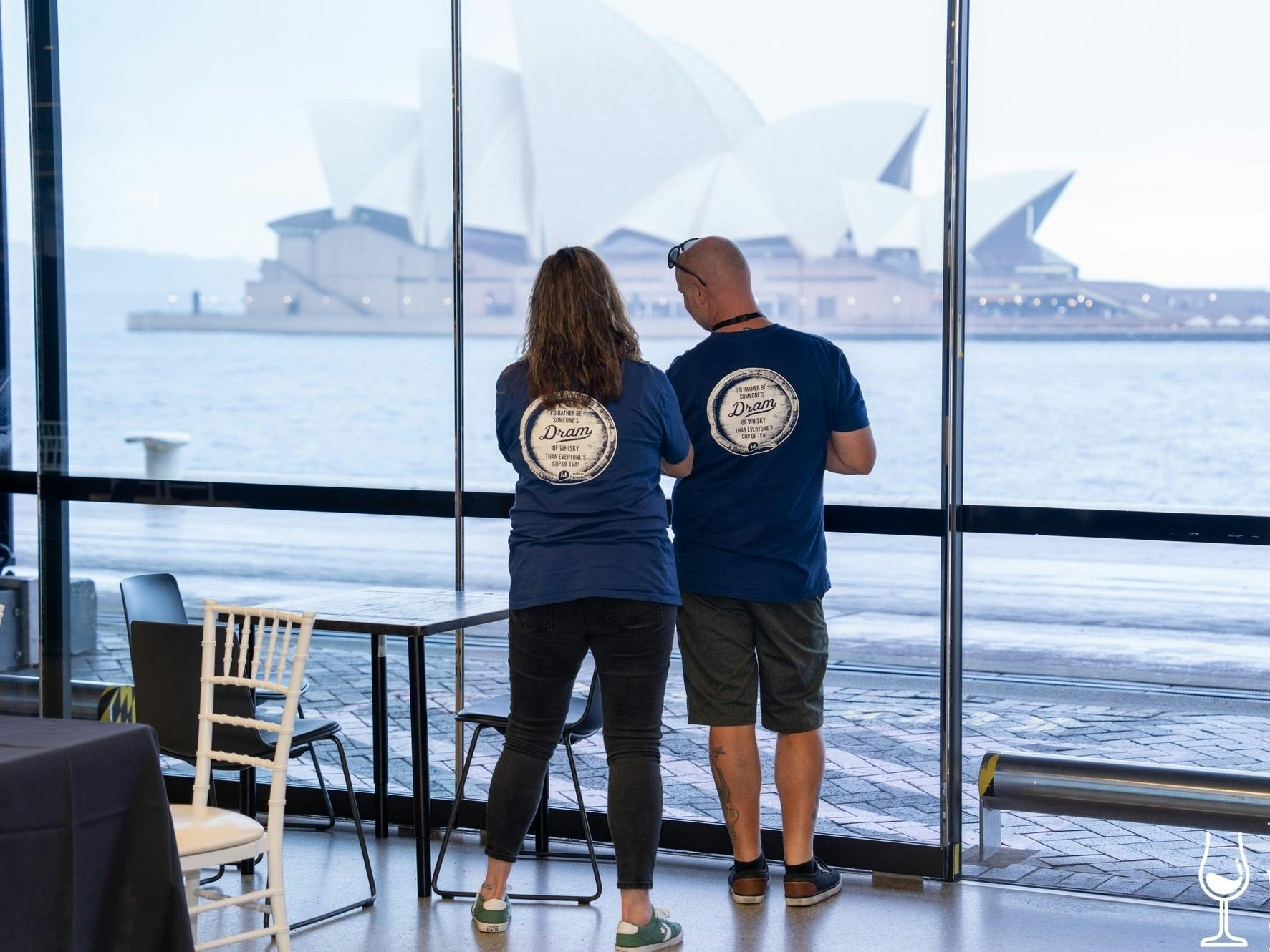 一緒に立っているカップルが、港の向こうのショー会場からの景色を眺めています。