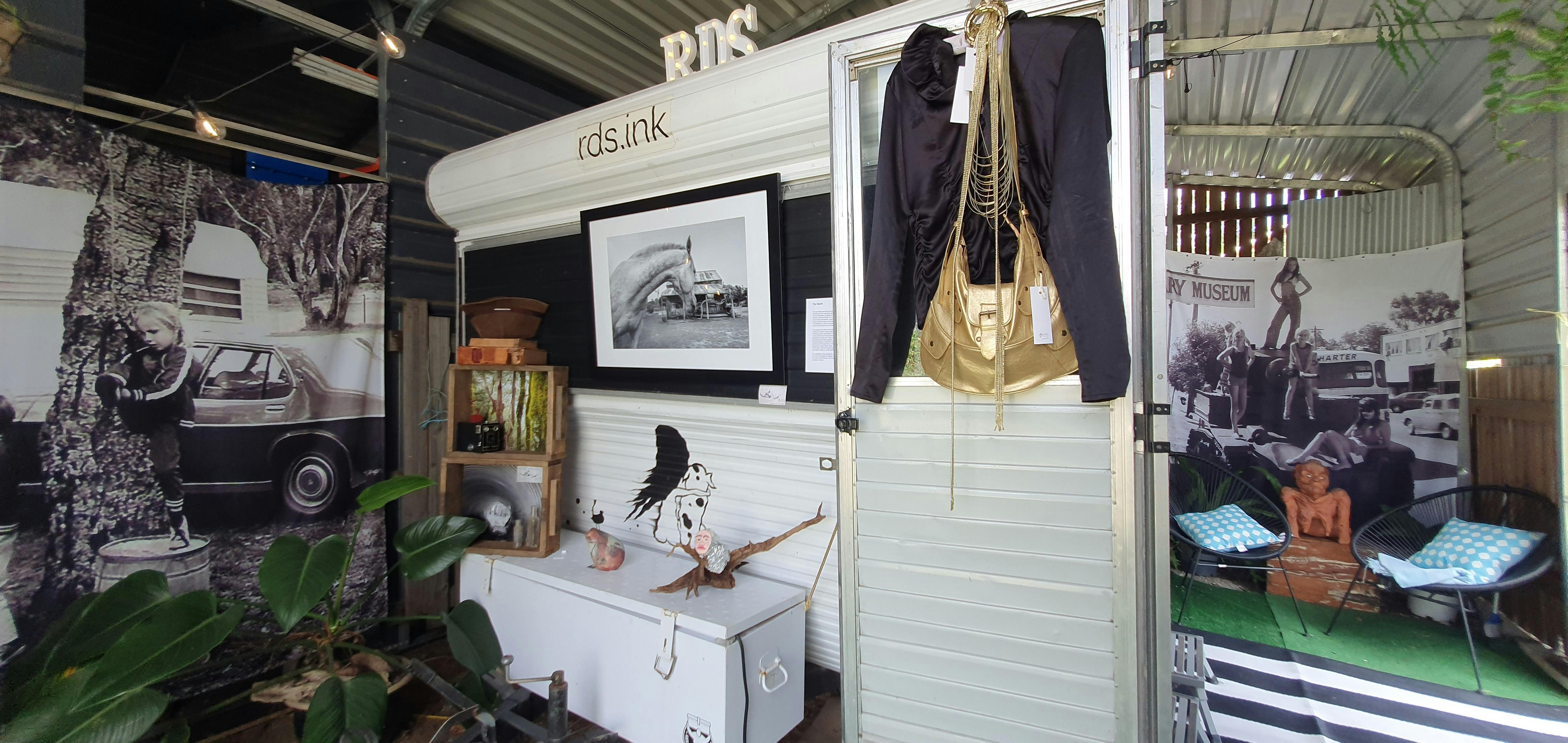 A vintage black and white caravan set up as a gallery