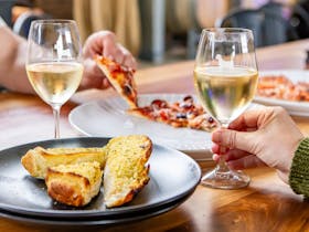 A table enjoying pizza, garlic bread and wine