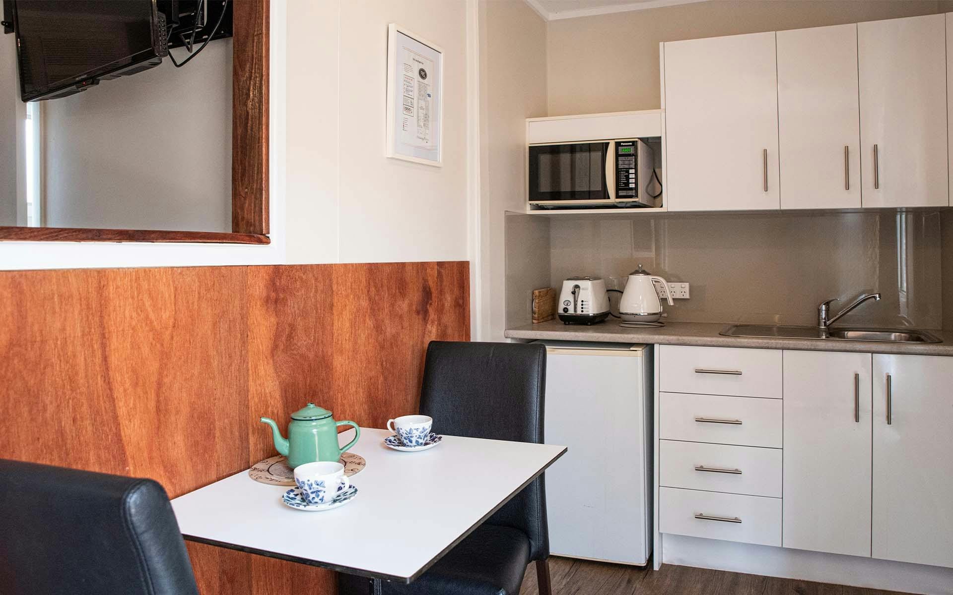 The Coach Inn room kitchen with a table and chairs, a kettle, toaster and sink