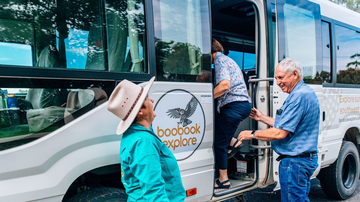 Meryl Eddie laughing with a guest boarding a Boobook Explore bus in Outback Queensland