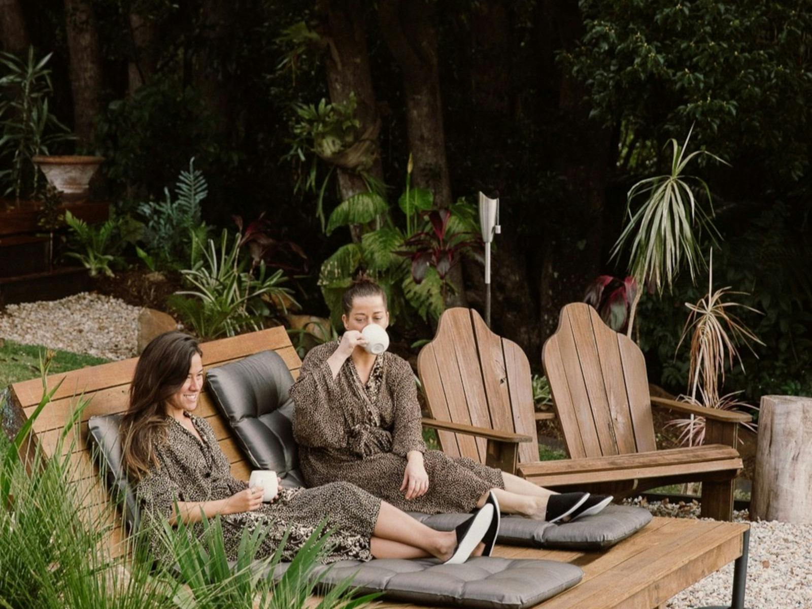 two women relaxing on garden deck chairs in garden