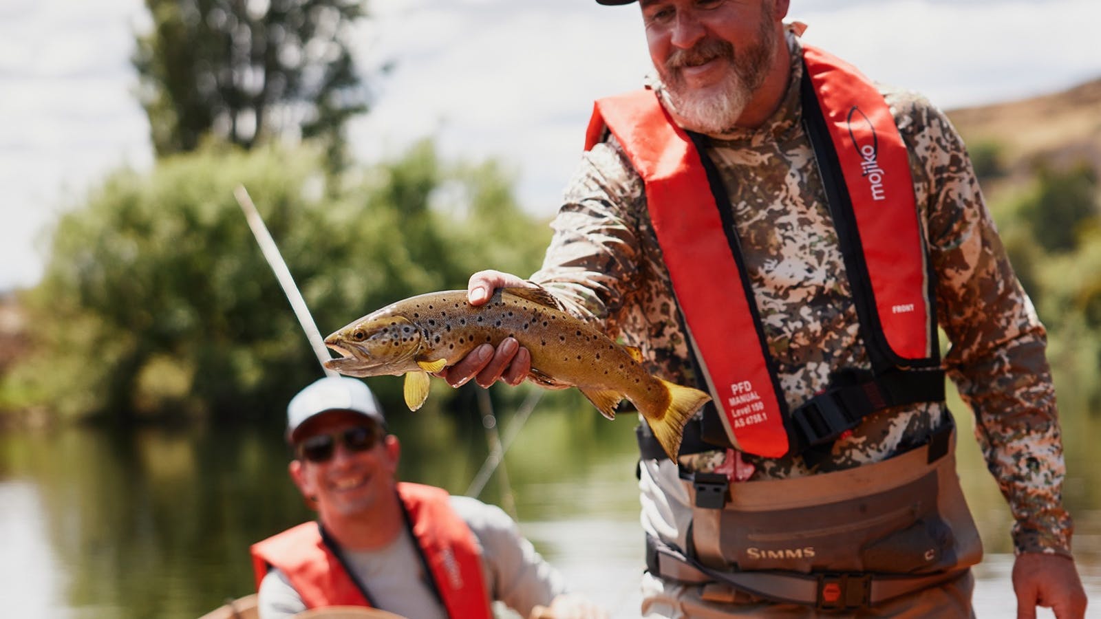 Marcus Saunders holding up a Brown trout in his drift boat, Tasmania