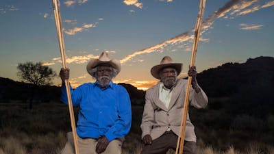 Two first nations elders in sitting in country near Amaroona at sunset with hand carved spears