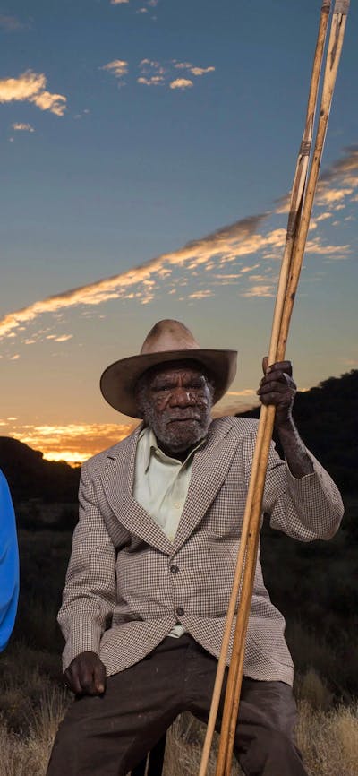 Two first nations elders in sitting in country near Amaroona at sunset with hand carved spears