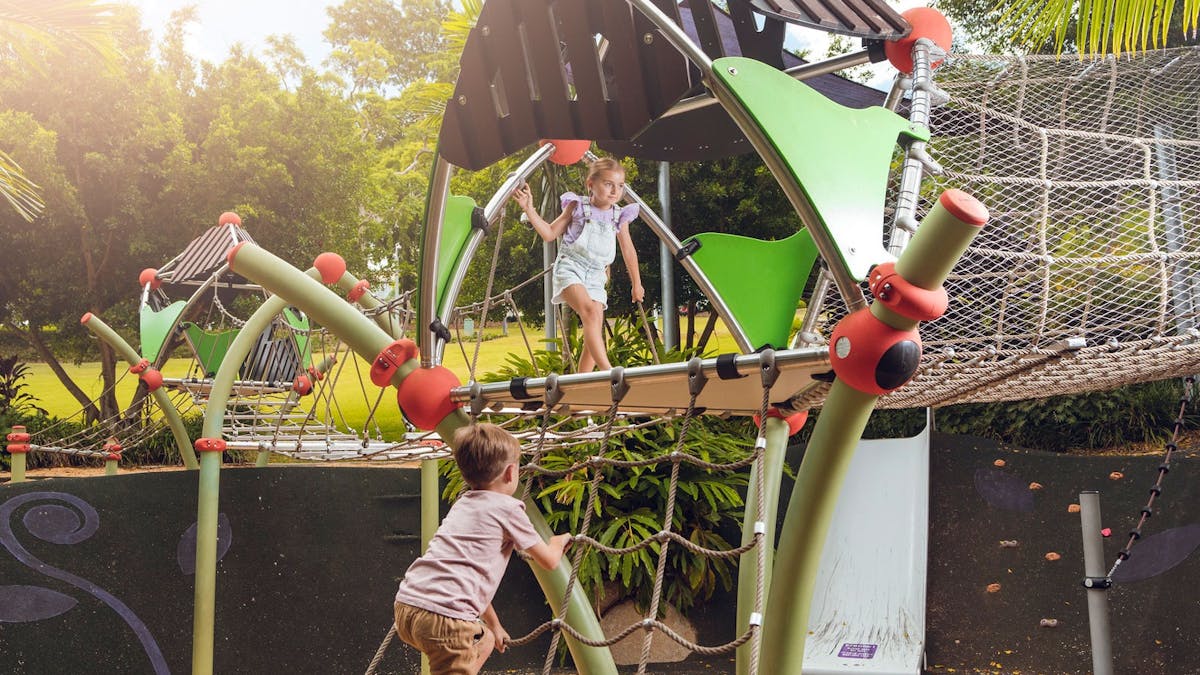 Two children playing on playground equipment in a park