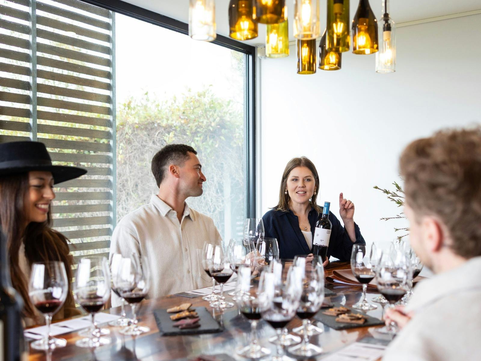 Group sitting at table for wine tasting experience at Gemtree Wines. Host talking about a bottle.