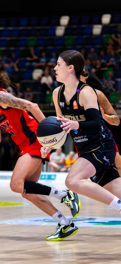 UC Capitals player driving to the basket for a layup during a WNBL game.