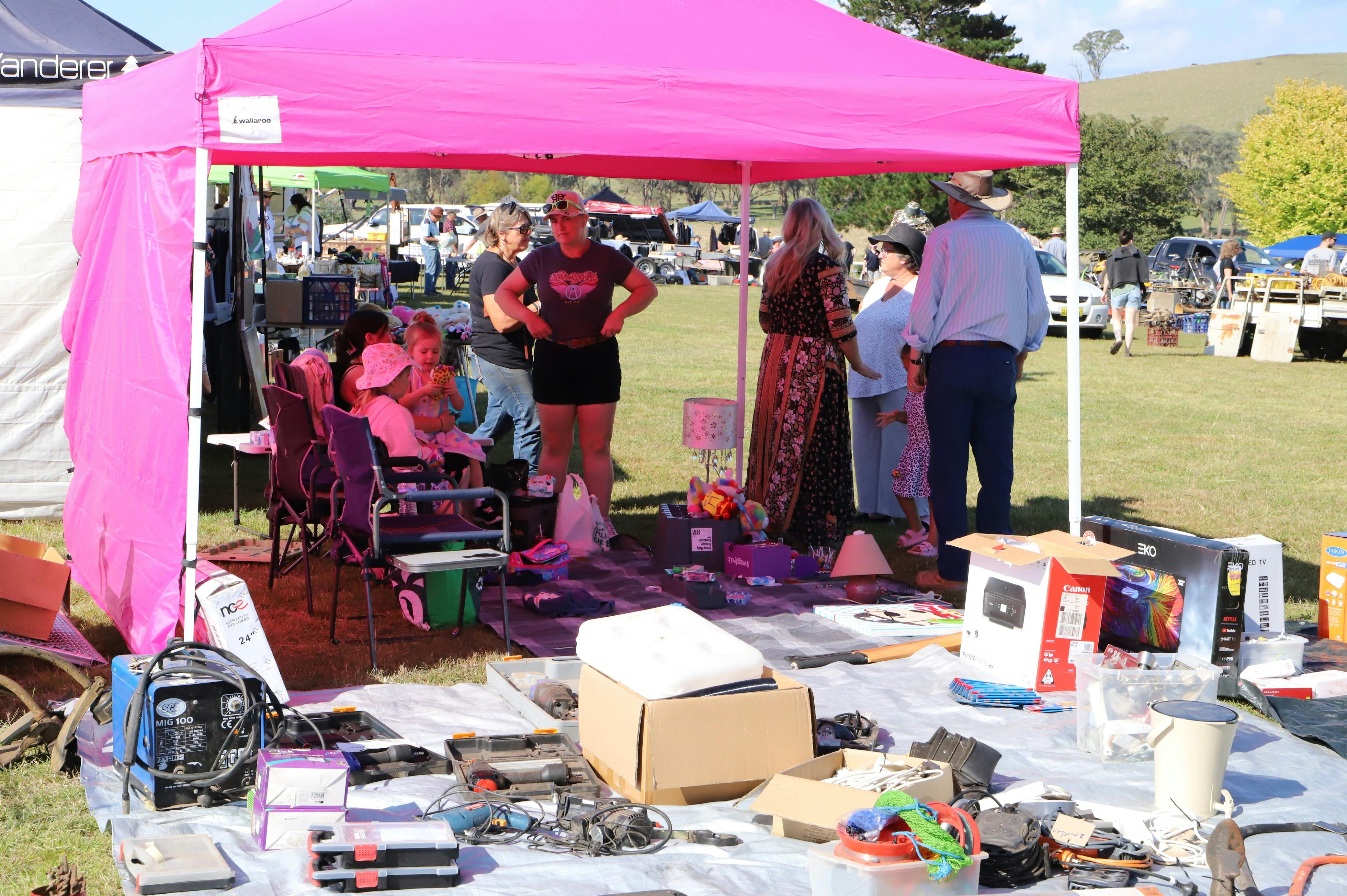 Bright pink marquee and backing sheet throwing a pink glow on five people sitting and standing