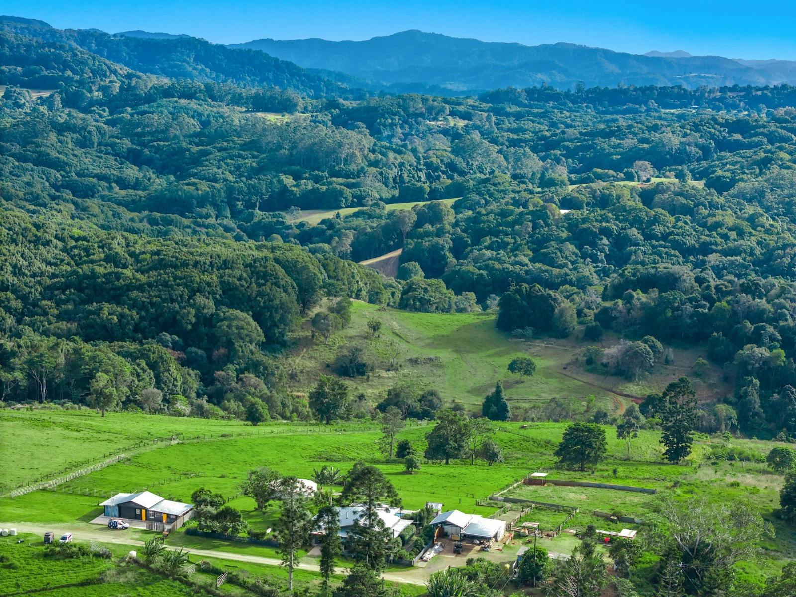 A mountain in the distance on a sunny day, with a green valley and some houses in the foreground