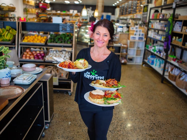 Waitress carrying healthy food with pottery, fruit and vegetables and groceries behind her